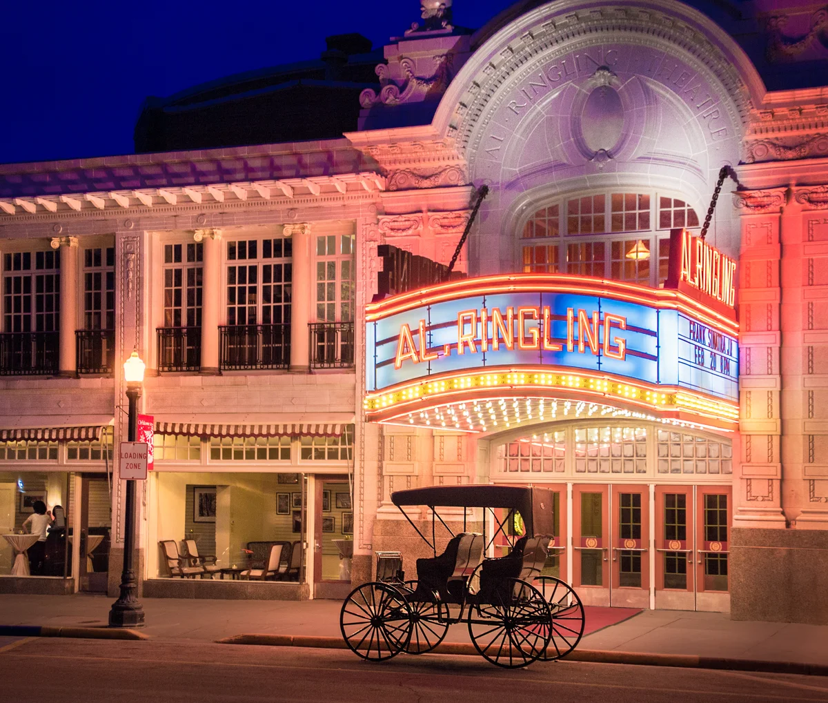 exterior view of movie theater with antique stage coach parked in front
