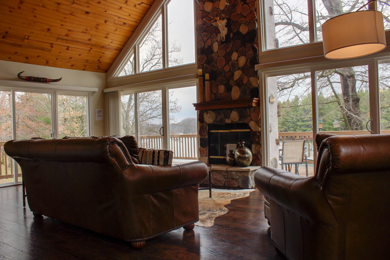 large fireplace and lounge chairs in a lodge with view of the woods