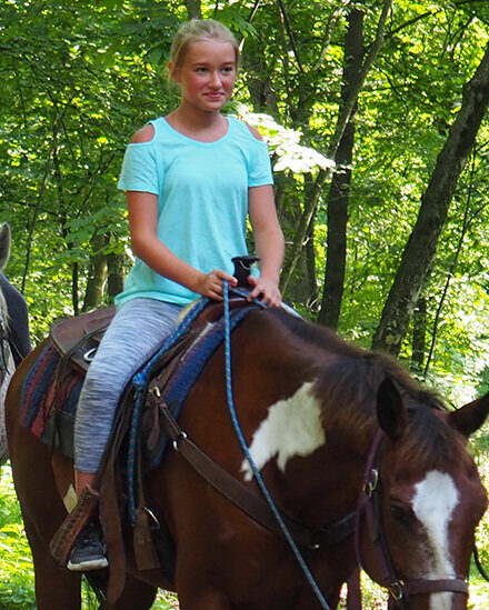 girl riding a horse in the woods