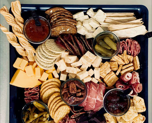 charcuterie board of cheeses, meats, crackers and pickles