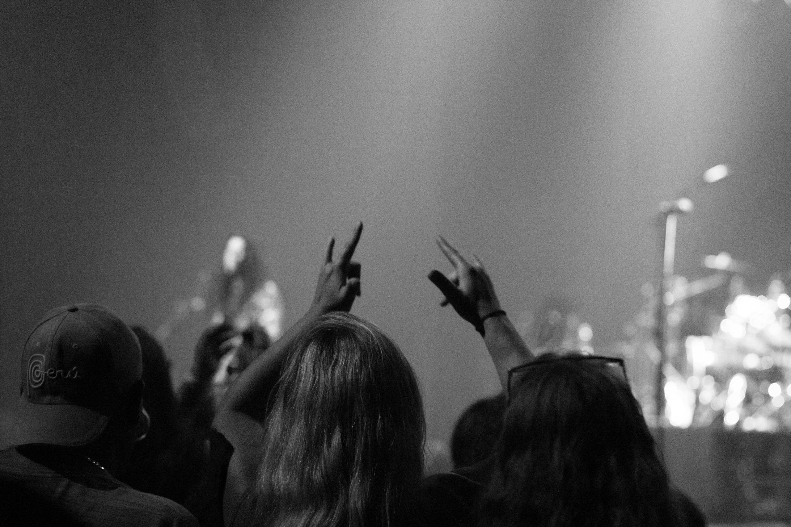 two women raise their pinky and index fingers at a rock concert