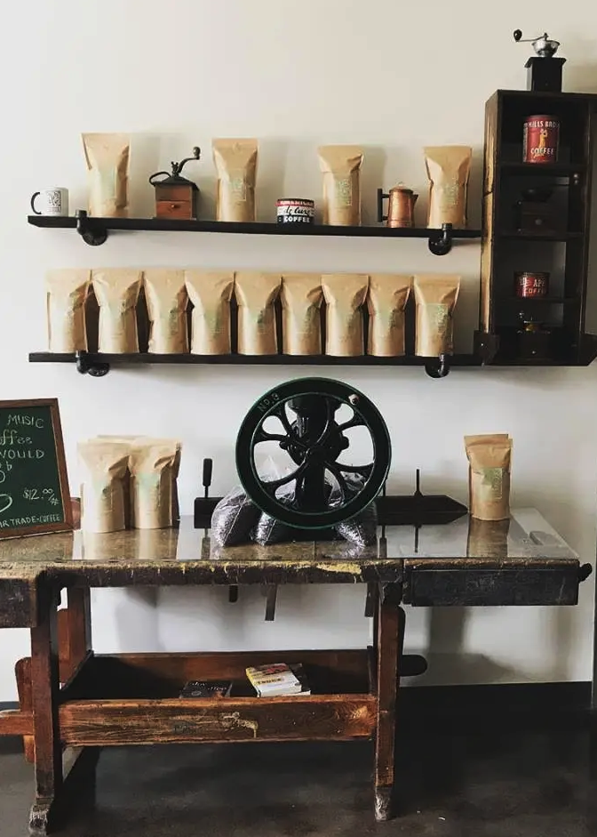 shelves of brown paper packaged coffee above an antique wooden table