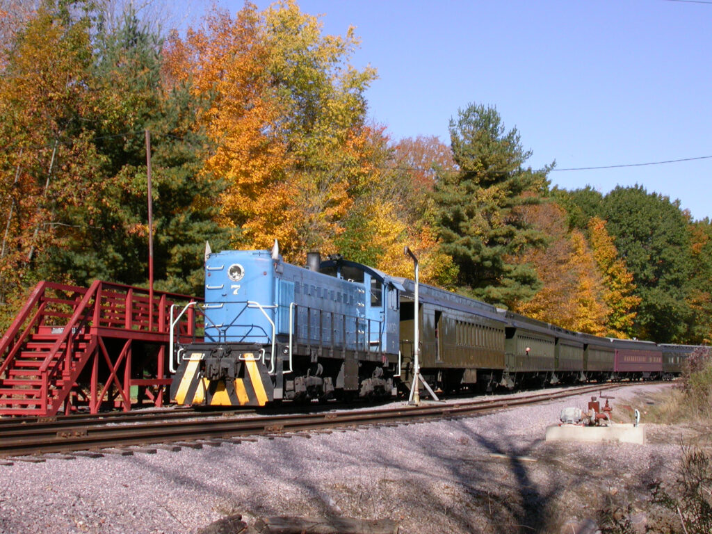 train on tracks next to fall-colored trees